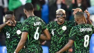 Les joueurs nigérians célèbrent pendant un match, portant leurs maillots noirs et verts vifs, montrant l'esprit d'équipe et la camaraderie.