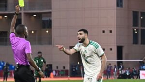 Le joueur algérien proteste alors que l'arbitre montre un carton jaune pendant un moment tendu du match, montrant l'atmosphère intense du jeu.