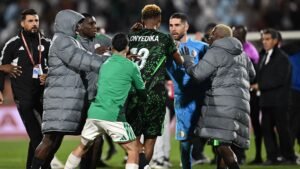 Les joueurs du Nigeria et de l'Algérie se confrontent après le match, montrant une forte tension. Des maillots verts et noirs notables sont présents.