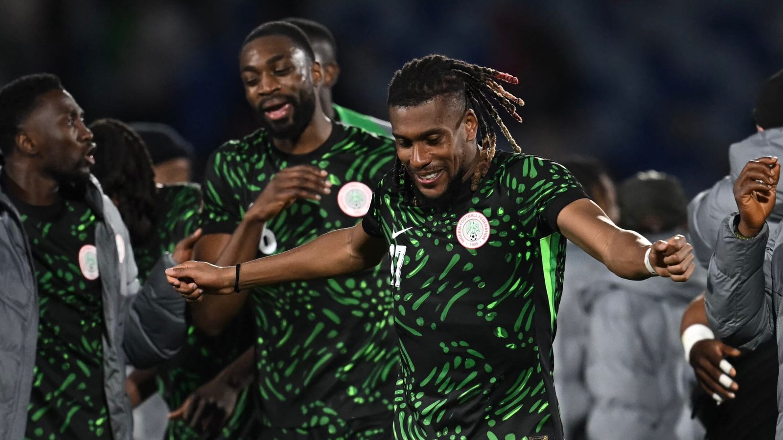 Les joueurs de football nigérians célèbrent dans leur tenue vert vif, exprimant la joie et l'esprit d'équipe après une victoire en match.