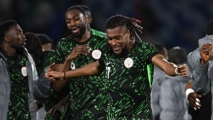 Les joueurs nigérians célèbrent ensemble, portant leur maillot vert vif avec des motifs uniques, montrant joie et camaraderie après un match.