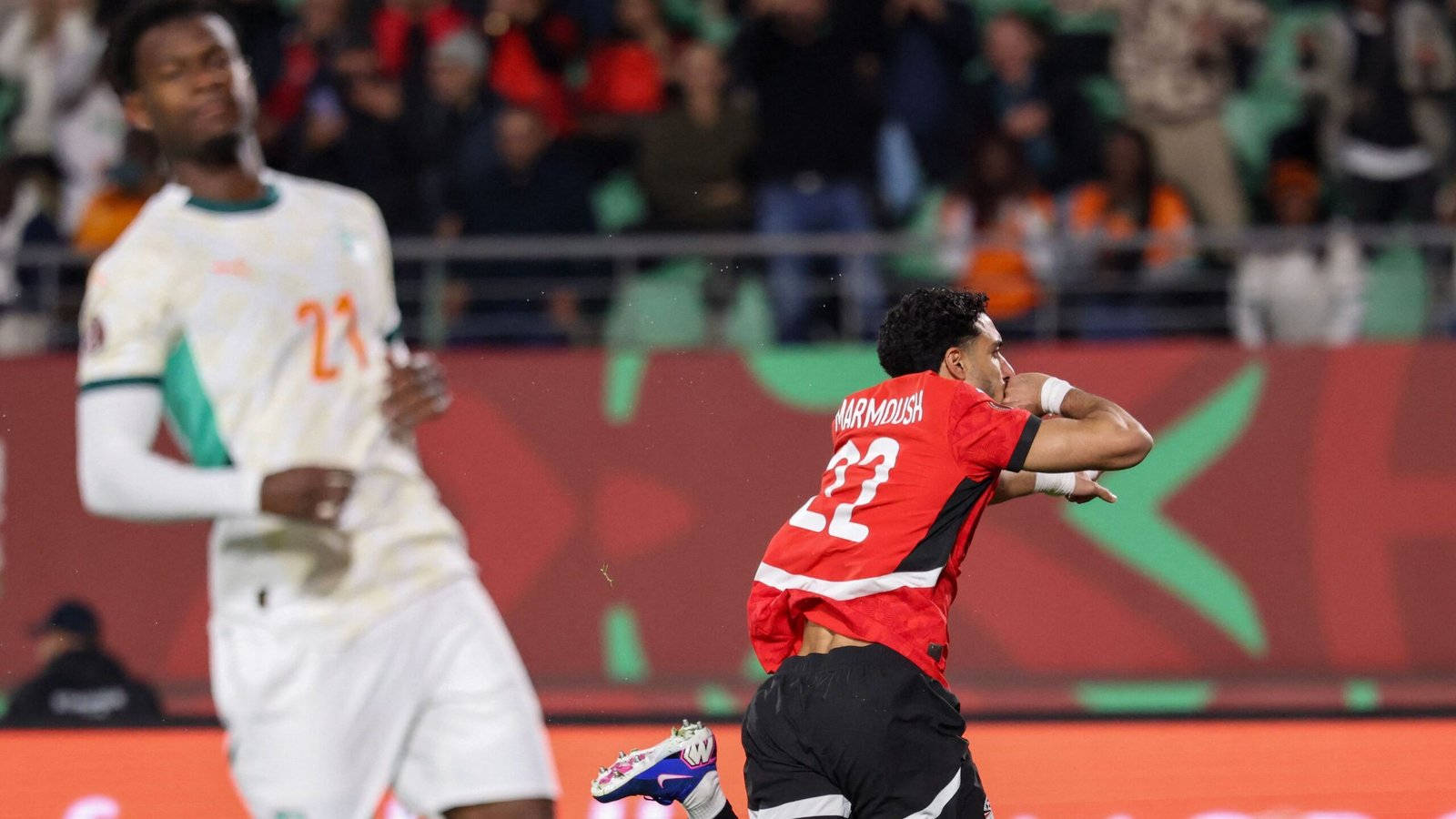 Le joueur marocain Abdelhamid Sabiri célèbre après avoir marqué, portant un maillot rouge avec "Narmdouch" dans le dos, contre un adversaire de la Côte d'Ivoire.