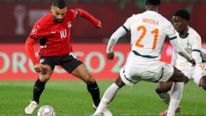 Mohamed Salah d'Égypte, en maillot rouge, dribble past deux défenseurs ivoiriens, Ndicka et Kessie, lors d'un match intense de la CAN.