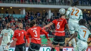 Le joueur marocain Yasser (6) conteste une tête avec Guessand (22) de la Côte d'Ivoire lors d'un match de qualification tendu pour la Coupe d'Afrique des Nations, avec des fans regardant.