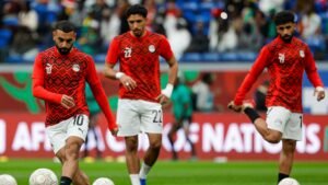 Egyptian players, including number 10, warm up in vibrant red kits with geometric patterns ahead of an Africa Cup of Nations match.