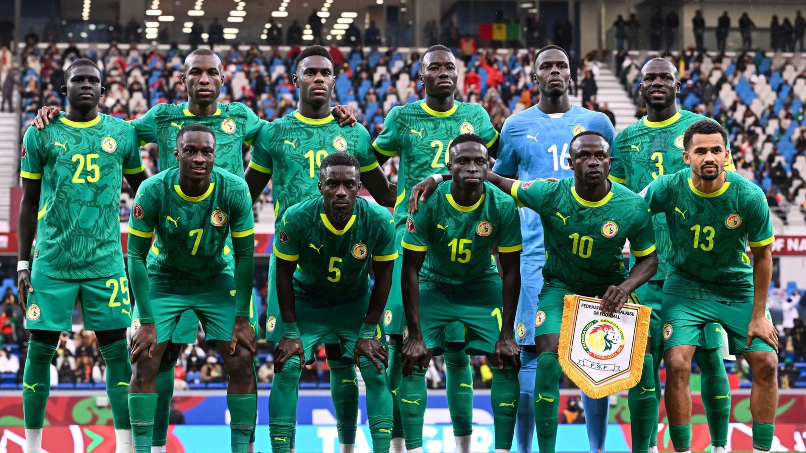Senegal's national football team poses for a photo in their green kits with yellow details, displaying team spirit before a match.