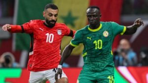 Sadio Mané in green competes for the ball with Mohamed Magdy in red during an intense match, showcasing Egypt vs Senegal rivalry.
