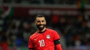 Mohamed Salah sourit dans le maillot rouge de l'Égypte avec le numéro 10, célébrant un moment lors d'un match international.