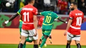 Sadio Mané célèbre un but dans le maillot vert vif du Sénégal face à l'Égypte, où l'on voit Mohamed Salah et ses coéquipiers en rouge.