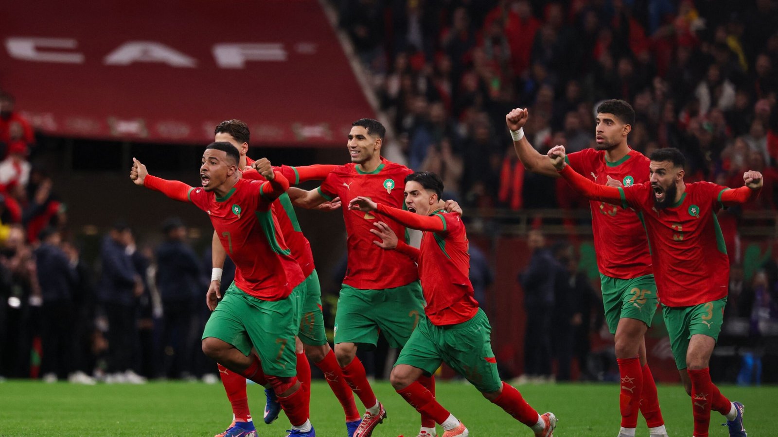 Moroccan players in vibrant red and green jerseys celebrate joyfully after a match, showcasing their excitement and team spirit.