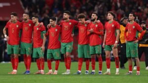 Morocco's national team stands united in their red and green kit, displaying emotional solidarity after a match.