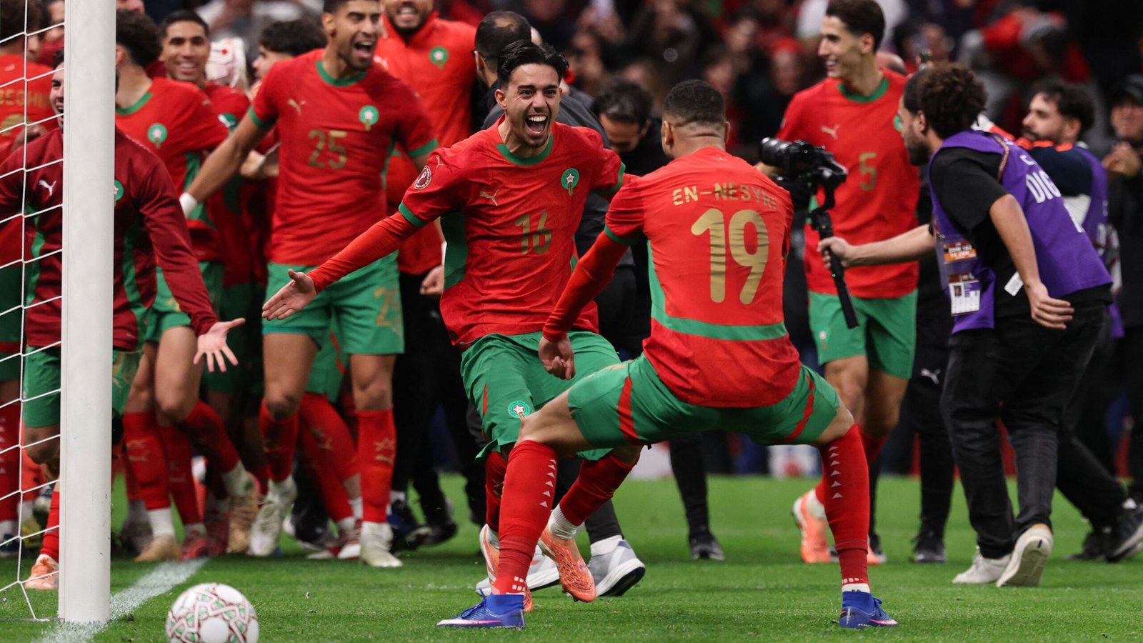 Les joueurs marocains célèbrent dans leurs maillots rouge et vert vif après un but, exprimant la joie et l'esprit d'équipe lors d'un moment de match euphorique.
