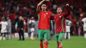 Achraf Hakimi et Bilal El Khannous célèbrent ensemble dans le maillot rouge et vert éclatant du Maroc après un match, illustrant l'esprit d'équipe et la joie.