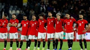 Egyptian national team lined up in red kits with the Egyptian flag, showing solidarity before a match, displaying determination and focus.
