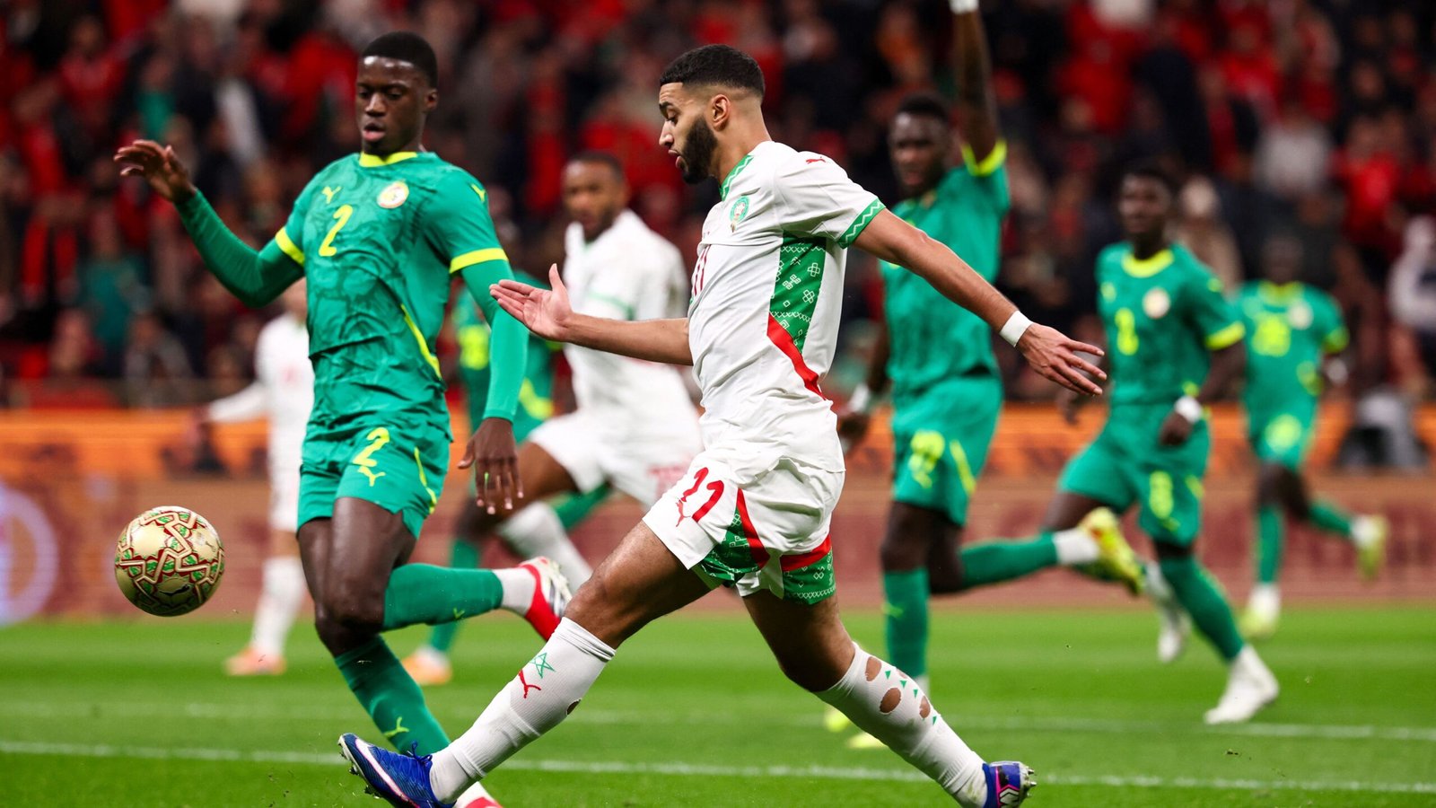 Morocco's player wearing number 11 dribbles past Senegal defenders in a vibrant match, showcasing intense competition and skill.