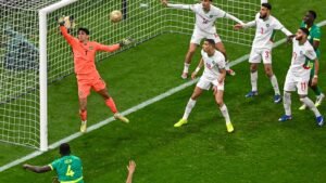 Morocco's goalkeeper makes a crucial save as teammates defend against an attacking player during a tense match scenario.
