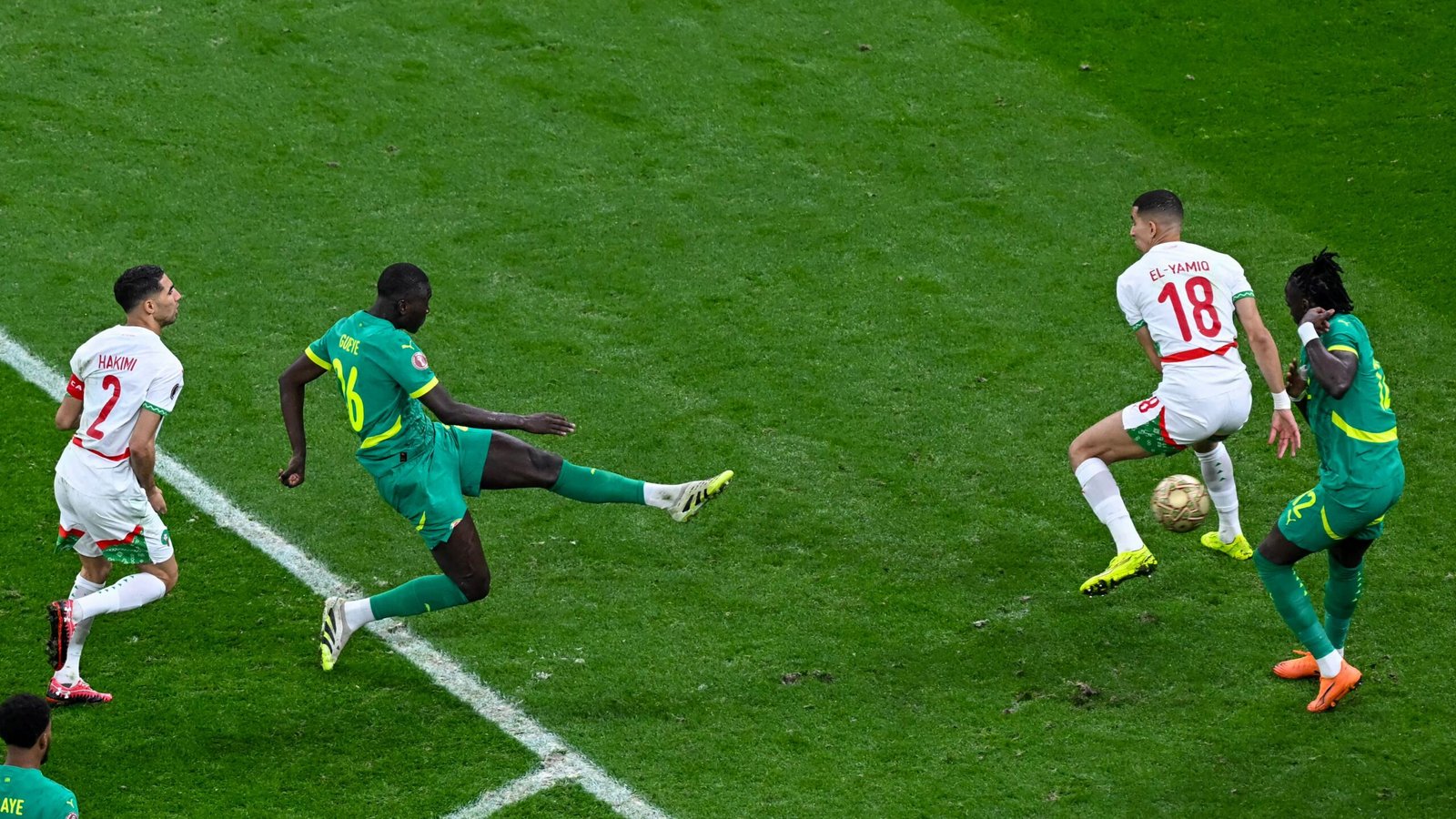 Hakimi and El-Yamiq of Morocco challenge a Senegalese player during a tense moment in their AFCON match, showcasing competitive action.