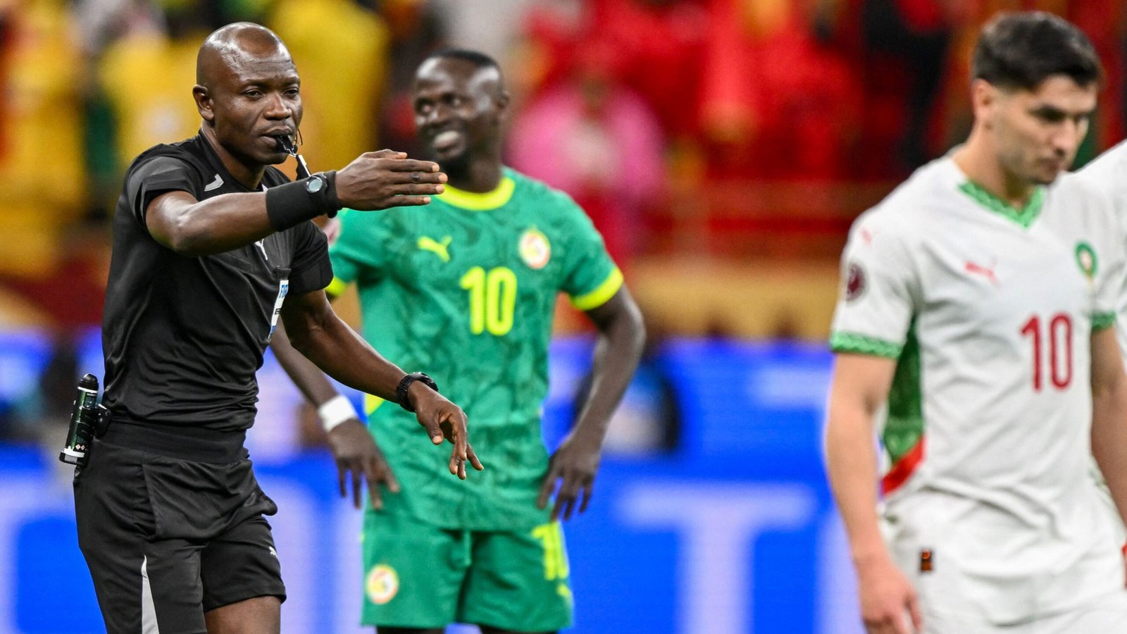 Referee signals during a moment of play, with Senegal's player in green and Morocco’s No. 10 in white, capturing the intensity of the match.
