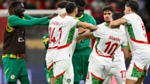 Morocco players surround Senegal's goalkeeper, showing tension and determination during a heated moment in an international match.