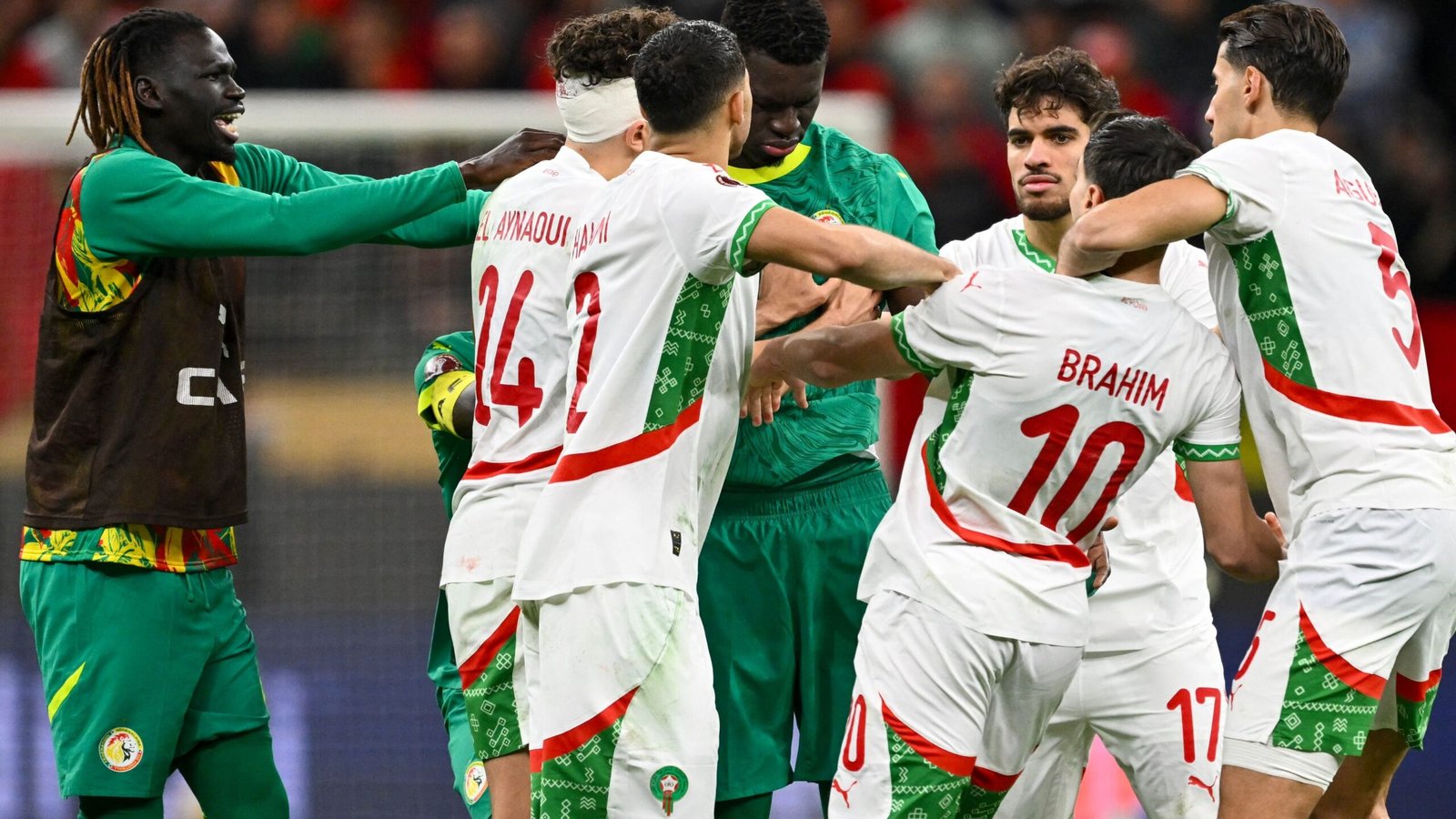 Morocco players surround Senegal's goalkeeper, showing tension and determination during a heated moment in an international match.
