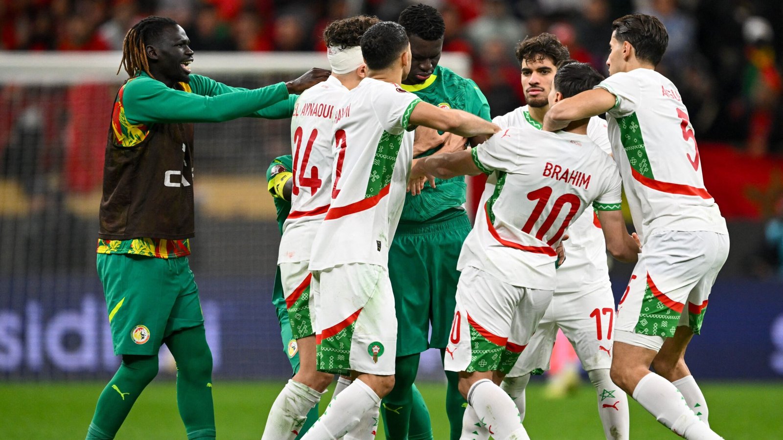 Les joueurs marocains célèbrent après un but, vêtus de leurs tenues blanches et vertes, dans une atmosphère de joie qui envahit le stade.