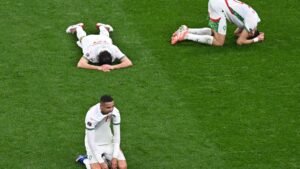 Les joueurs marocains affichent leur abattement sur le terrain, l'un agenouillé au premier plan tandis que d'autres sont allongés face contre terre sur la pelouse, reflétant leur déception.