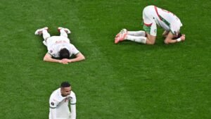 Les joueurs marocains visiblement abattus sur le terrain après un match, l'un allongé face contre terre et deux autres au désespoir à genoux.