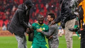 Sadio Mané du Sénégal célèbre joyeusement avec ses coéquipiers après une victoire, sous une pluie battante, illustrant l'émotion et l'esprit d'équipe.