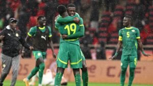 لاعبو السنغال يحتفلون بزي أخضر تحت المطر، بينما يعانق أحد اللاعبين زميله مرتدياً القميص رقم 19، في مشهد يعبر عن البهجة أثناء المباراة.