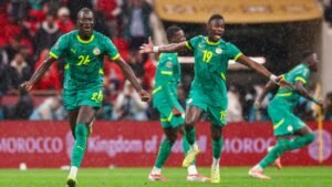 Senegal players celebrate in vibrant green kits during a rainy match, showcasing joy and excitement in a thrilling moment.