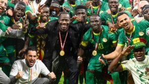 Senegal's blijde spelers vieren hun Afrika Cup-overwinning, gekleed in groene tenues en gouden medailles, tussen confetti en regen.