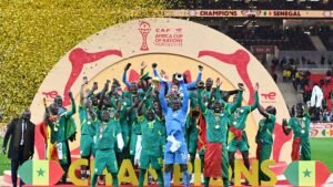 Les joueurs sénégalais célèbrent sur le podium avec le trophée de la Coupe d'Afrique des Nations, parés de médailles et entourés de confettis, après leur victoire dans le tournoi.