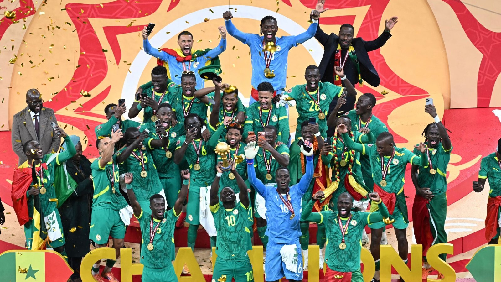 Les joueurs sénégalais célèbrent leur victoire en Coupe d'Afrique des Nations, brandissant le trophée, tandis qu'une pluie de confettis dorés tombe autour d'eux.