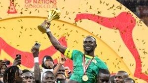 Sadio Mané celebrates Senegal's victory, lifting the Africa Cup of Nations trophy amidst confetti and cheering teammates.