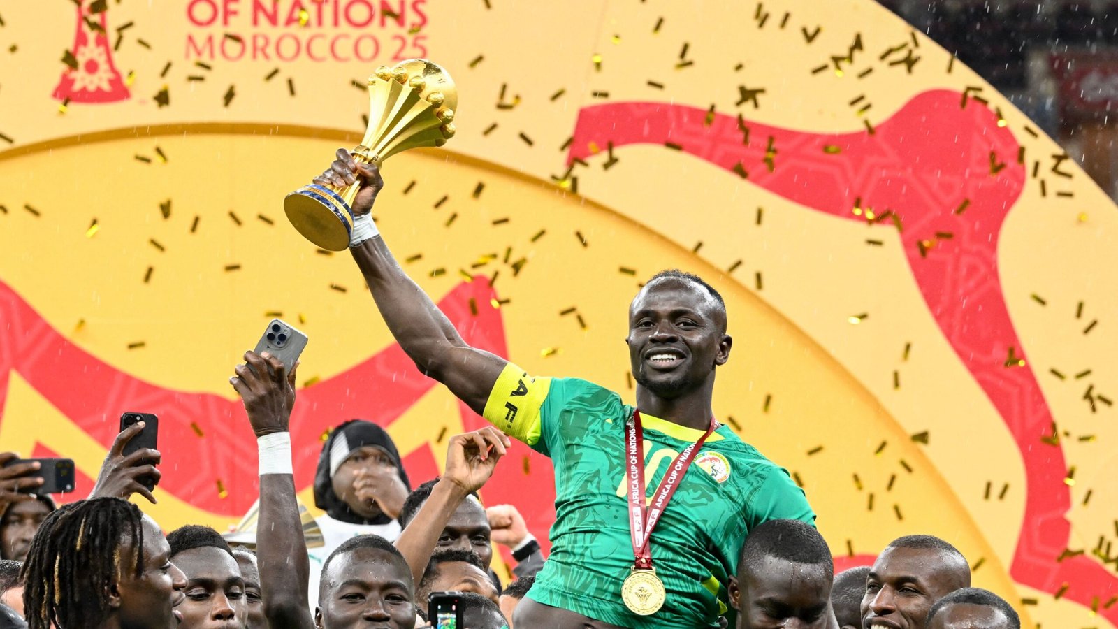 Sadio Mané celebrates Senegal's victory, lifting the Africa Cup of Nations trophy amidst confetti and cheering teammates.