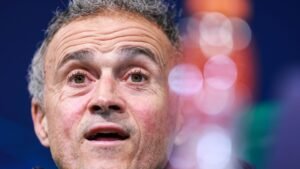 Luis Enrique passionately speaking at a press conference, with vivid bokeh effects in the background highlighting his expressive features.