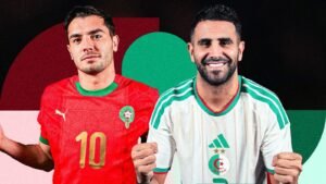 Riyad Mahrez in Algeria's white kit smiles alongside a Moroccan player in a red kit, both showcasing their national pride.