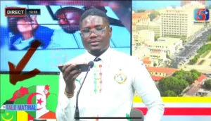 Un analyste football en direct discute des équipes nord-africaines. L'arrière-plan présente des drapeaux, des cartes et une vue urbaine. Studio coloré.