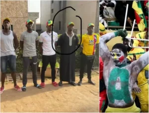 Un groupe de supporters du Sénégal, portant les couleurs de l'équipe et des casquettes. Un fan est vêtu d'un habit traditionnel, tandis qu'un autre a le visage peint.