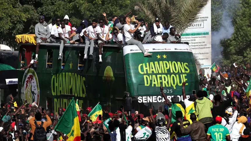 Célébrations au Sénégal où les supporters se rassemblent autour d'un bus arborant l'inscription "Champions d'Afrique", illustrant la fierté footballistique et l'unité nationale.