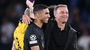 Achraf Hakimi célébrant avec l'entraîneur Luis Enrique après une victoire cruciale en Ligue des champions, affichant tous deux joie et camaraderie.