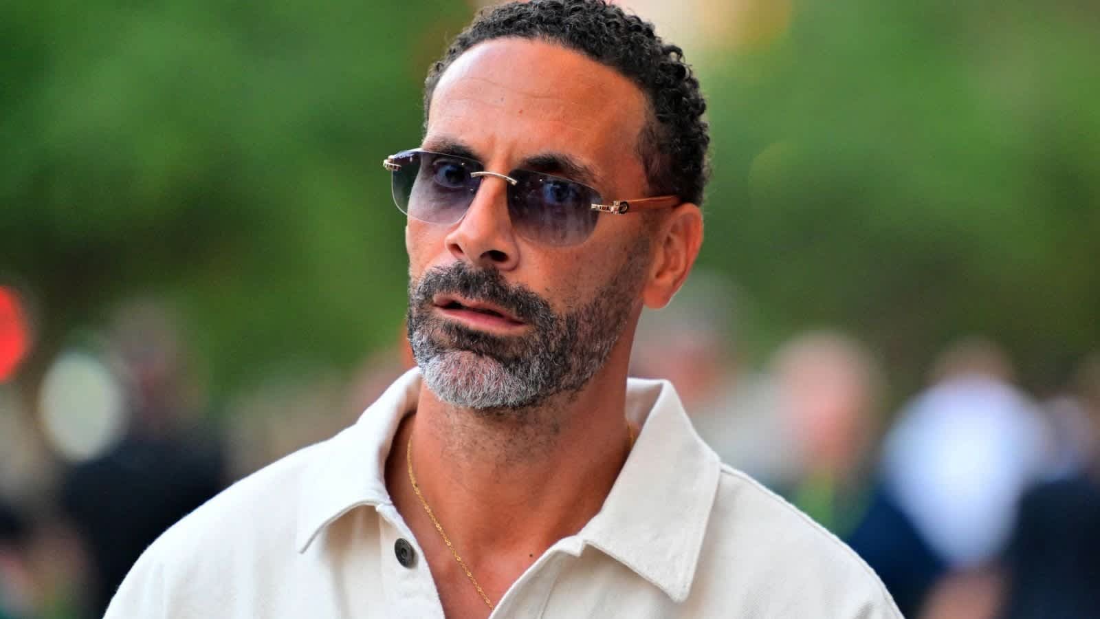 ريو فيرديناند يرتدي نظارات وقميصاً فاتح اللون، ينظر بتأمل إلى الأمام، على خلفية خارجية ضبابية.