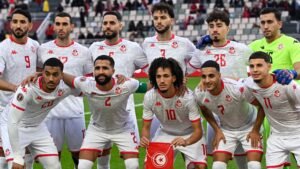 المنتخب التونسي لكرة القدم يلتقط صورة جماعية قبل المباراة بقمصان بيضاء مع لمسات حمراء، مما يظهر تركيز اللاعبين ووحدتهم.