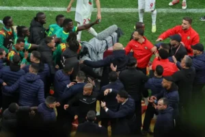 Moroccan and Senegalese players engage passionately near the sidelines, amidst a tense atmosphere during a major match.