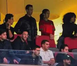 Moroccan fans watch a match, highlighting a woman in a red national team jersey, amidst others showing intense emotions from the stands.