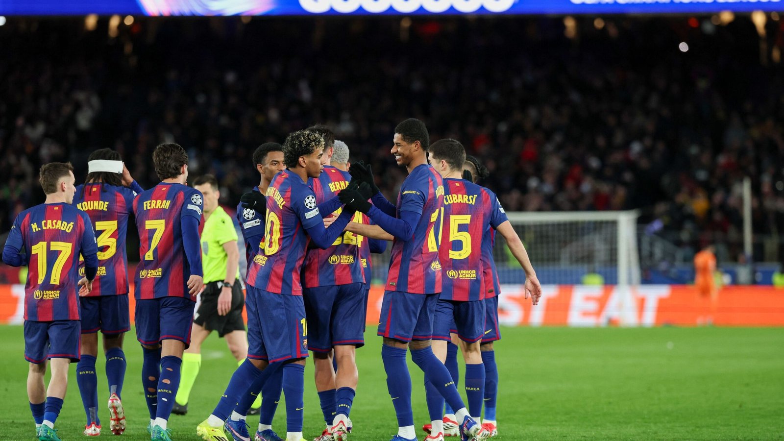 Barcelona-spelers vieren een doelpunt tijdens een UEFA Champions League-wedstrijd, waarbij ze hun blauw en granaatrode tenue tonen in een levendige stadionsfeer.