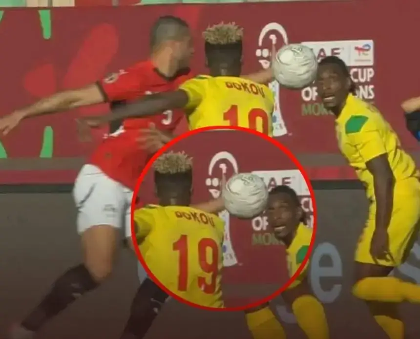 Een Marokkaanse speler in rood komt in botsing met twee tegenstanders in geel tijdens een intens moment op de Afrika Cup.