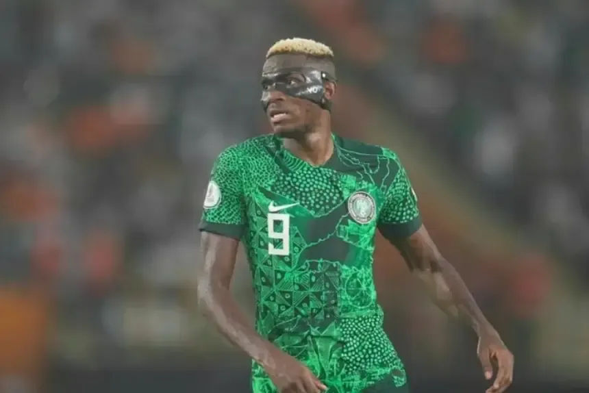 Victor Osimhen portant le maillot vert vif du Nigeria avec un motif décoratif, équipé d'un masque de protection pendant un match.