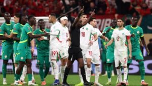 Morocco and Senegal players clash during a tense moment in the match, while the referee intervenes amid a vibrant stadium atmosphere.