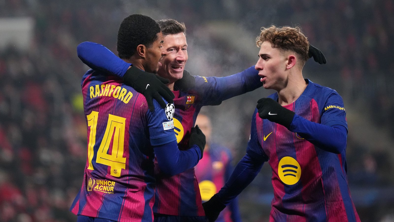 Juichende Barcelona-spelers Marcus Rashford, Robert Lewandowski en Pedri omhelzen elkaar in levendige paarse en blauwe tenues na een doelpunt.